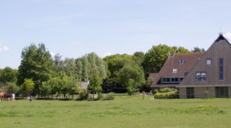 Zorgboerderij Bos en Meerzicht met ruim grasveld en karakteristieke boerderij omgeven door groen